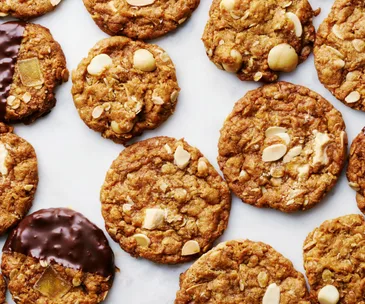 Anzac biscuits on a bench, some covered in chocolate