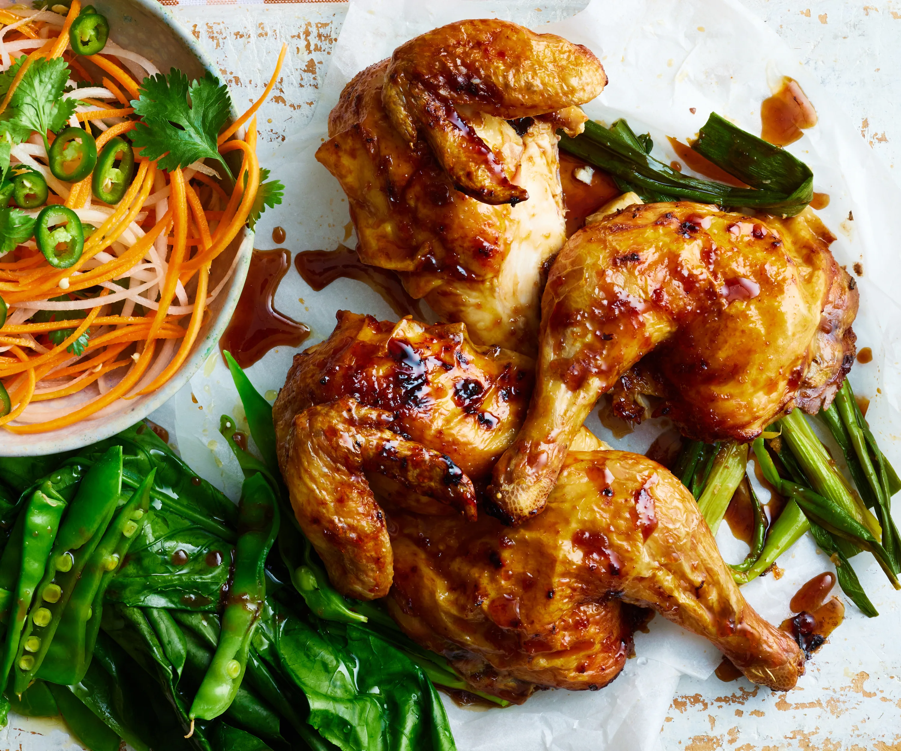 Butterflied soy & ginger chicken next to a bowl of carrot and daikon salad.