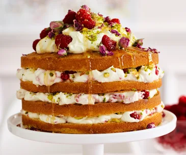 Rose & pistachio layer cake on a white cake stand.