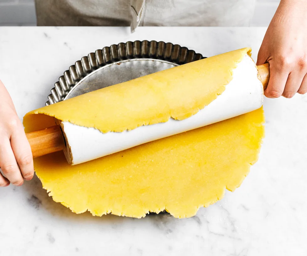 Pastry case being rolled out into tin with rolling pin