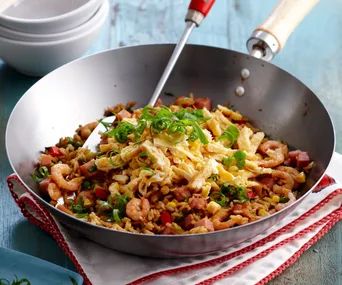 Fried rice in a wok topped with sliced omelet