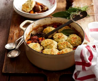 A pot of beef stew topped with dumplings