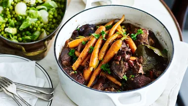 Beef in red wine in a casserole pot topped with carrots, one of our slow cooked beef recipes