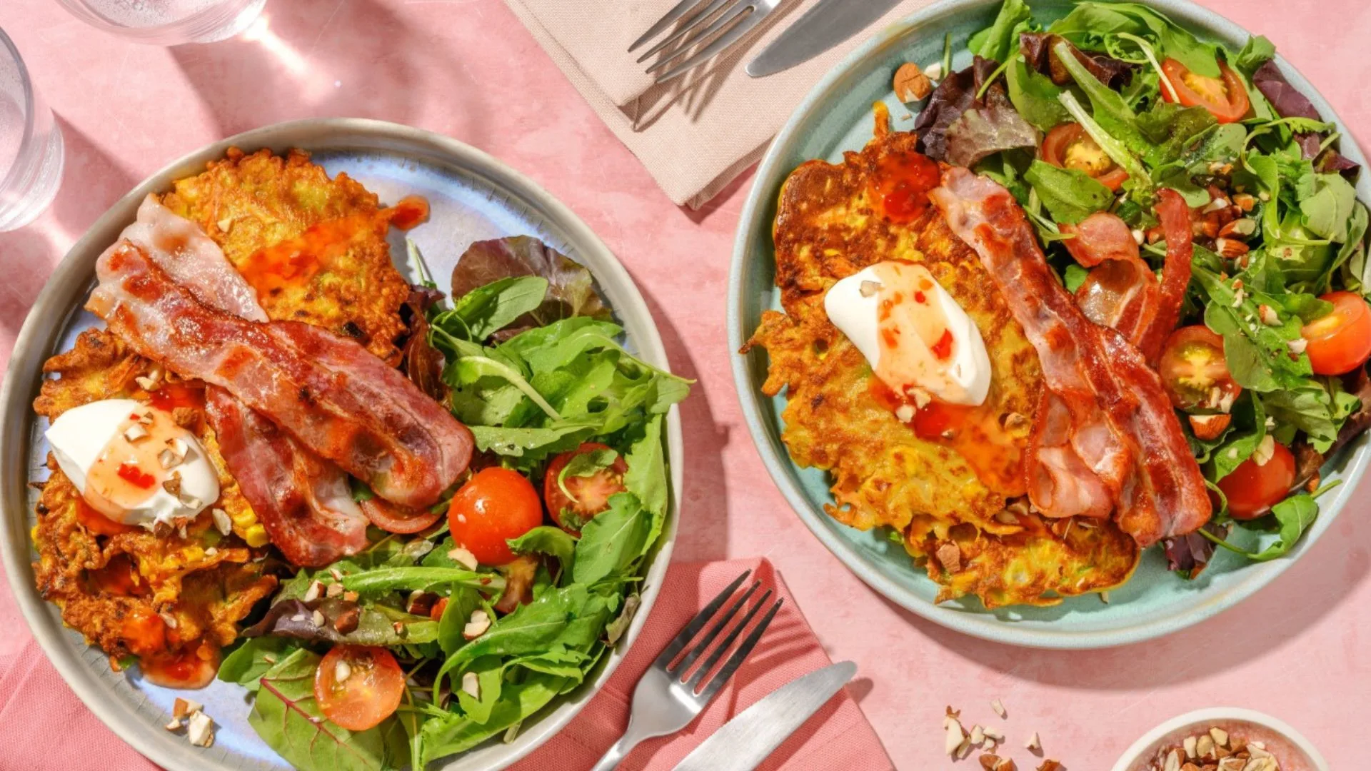Two bowls of Corn Fritter & Bacon Stacks from HelloFresh, set on a table with a pink tablecloth and napkins.