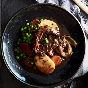 lamb stew slow cooker in a bowl with potato, carrot and peas