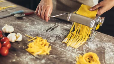 A close-up of someone using a pasta maker at home.