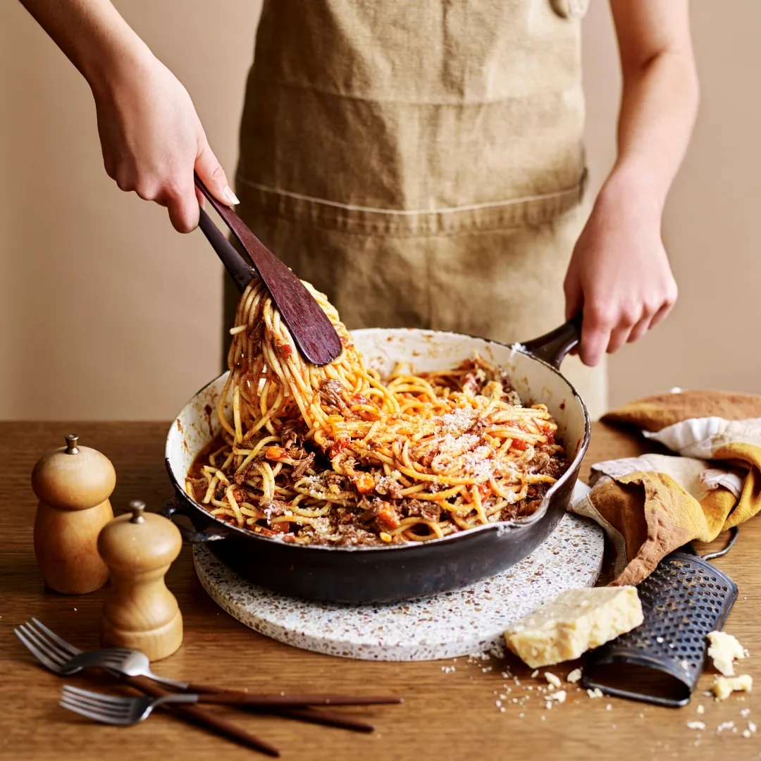 a person twirling stovetop beef ragu in a pan