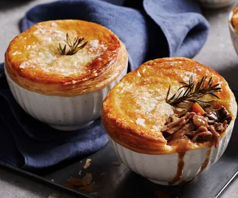 Two slow cooker beef pies in white ramekins