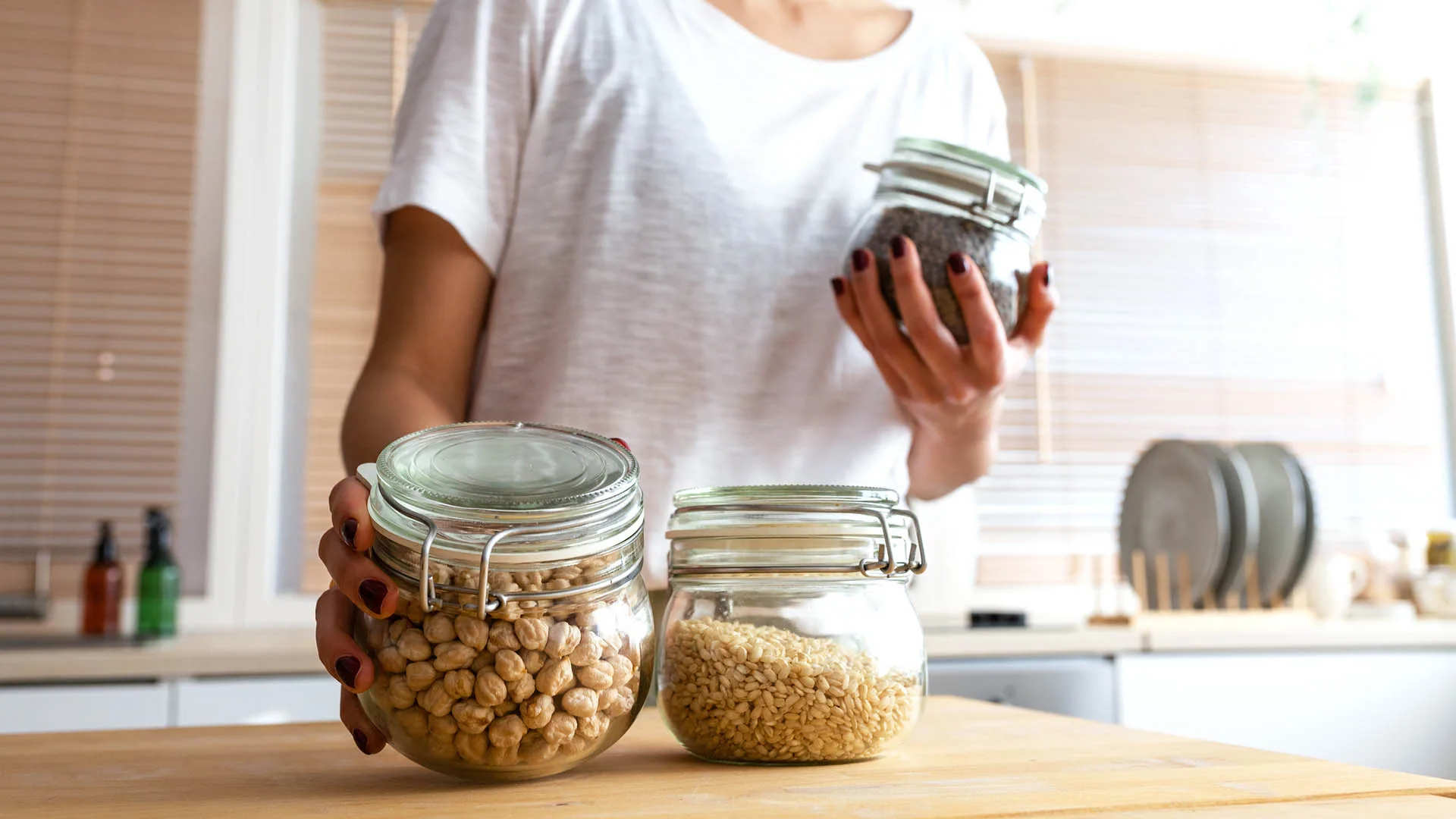 legumes in glass containers held by a woman