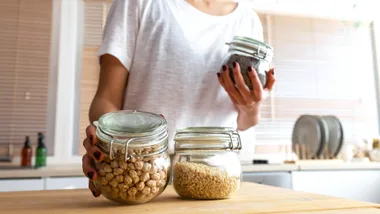 legumes in glass containers held by a woman
