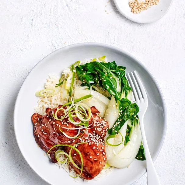 Soy and sriracha air fryer chicken on a plate with rice, pak choy and sesame seeds