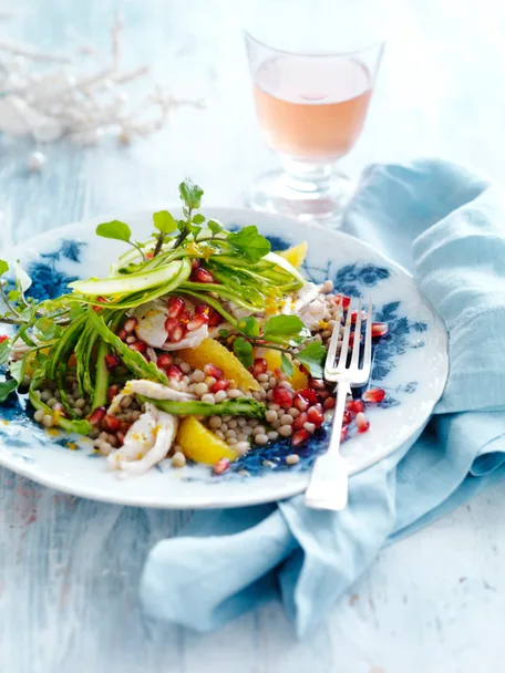 Pearl couscous salad with turkey and pomegranate on serving plate with fork