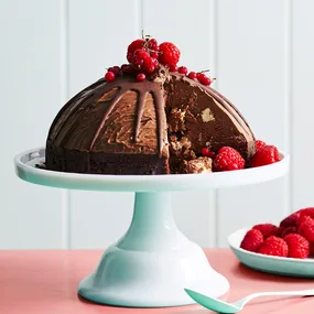 Choc mint ice-cream bombe with fresh raspberries on a cake stand