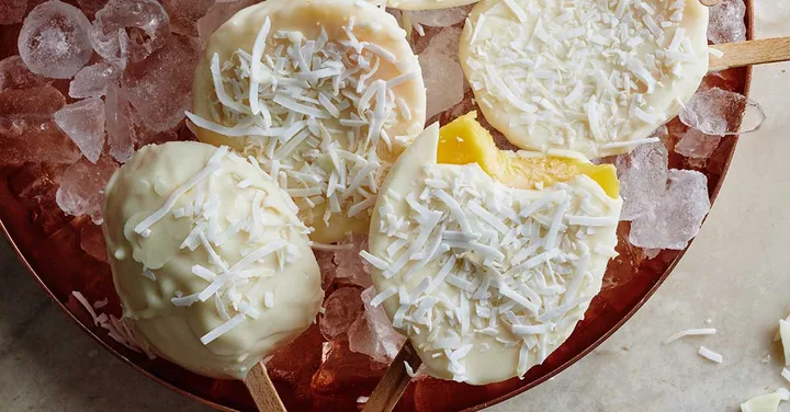 frozen mango covered in white chocolate on an ice cream stick