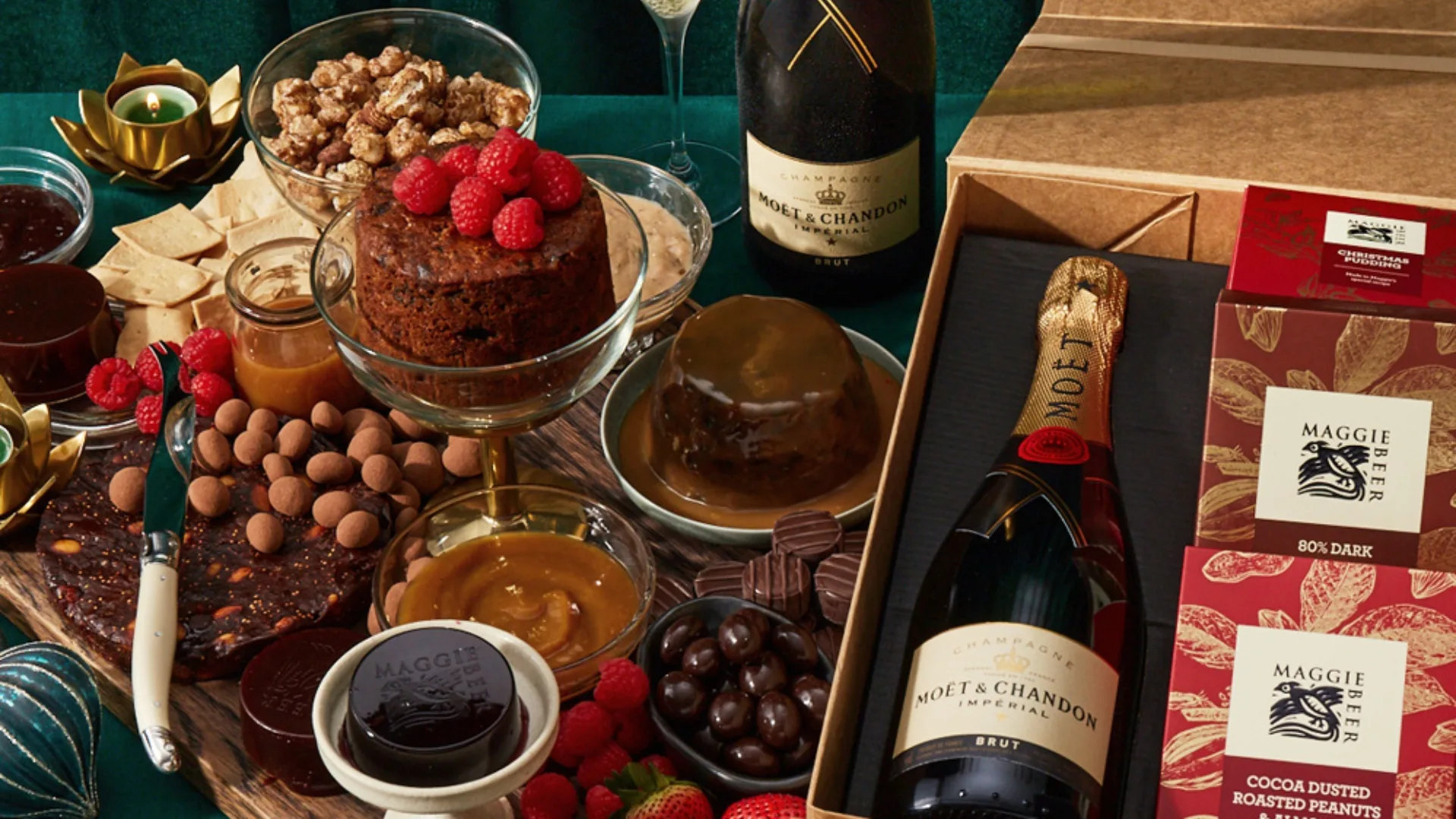 Luxury gift set with Moët & Chandon champagne, gourmet chocolates, nuts, and desserts on a green tablecloth.