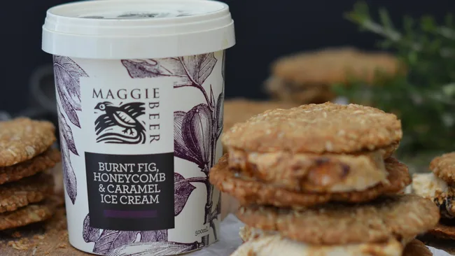 Maggie Beer Burnt Fig, Honeycomb & Caramel Ice Cream tub next to oat biscuits with ice cream filling.