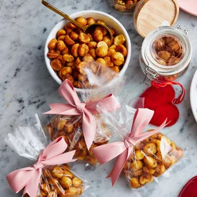 Spiced macadamias in a white bowl plus three gift bags