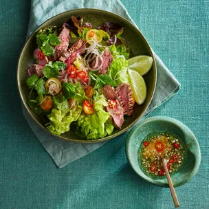 Thai beef salad with a bowl of chilli sauce