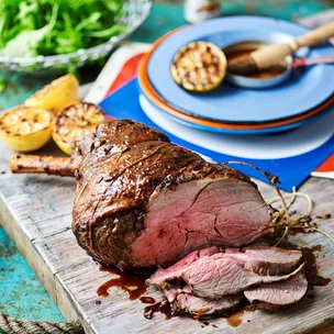 leg of lamb with grilled lemons on a chopping board