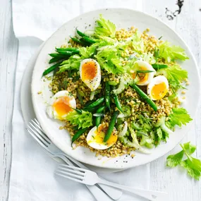 Green bean salad with farro, celery and boiled eggs in a white serving bowl.