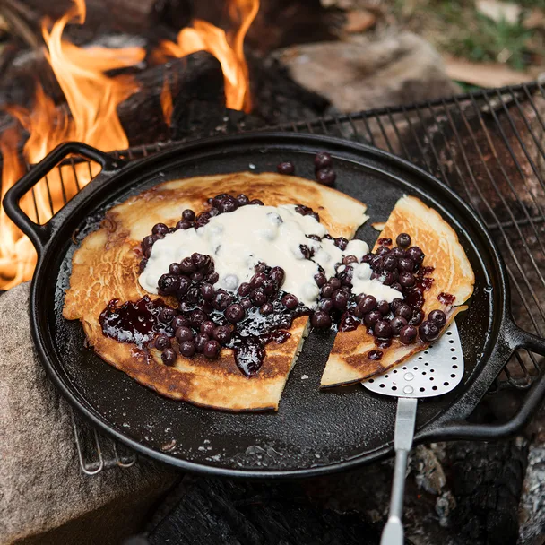 Blueberry pancake recipe cooked on campfire, served with blueberries and custard