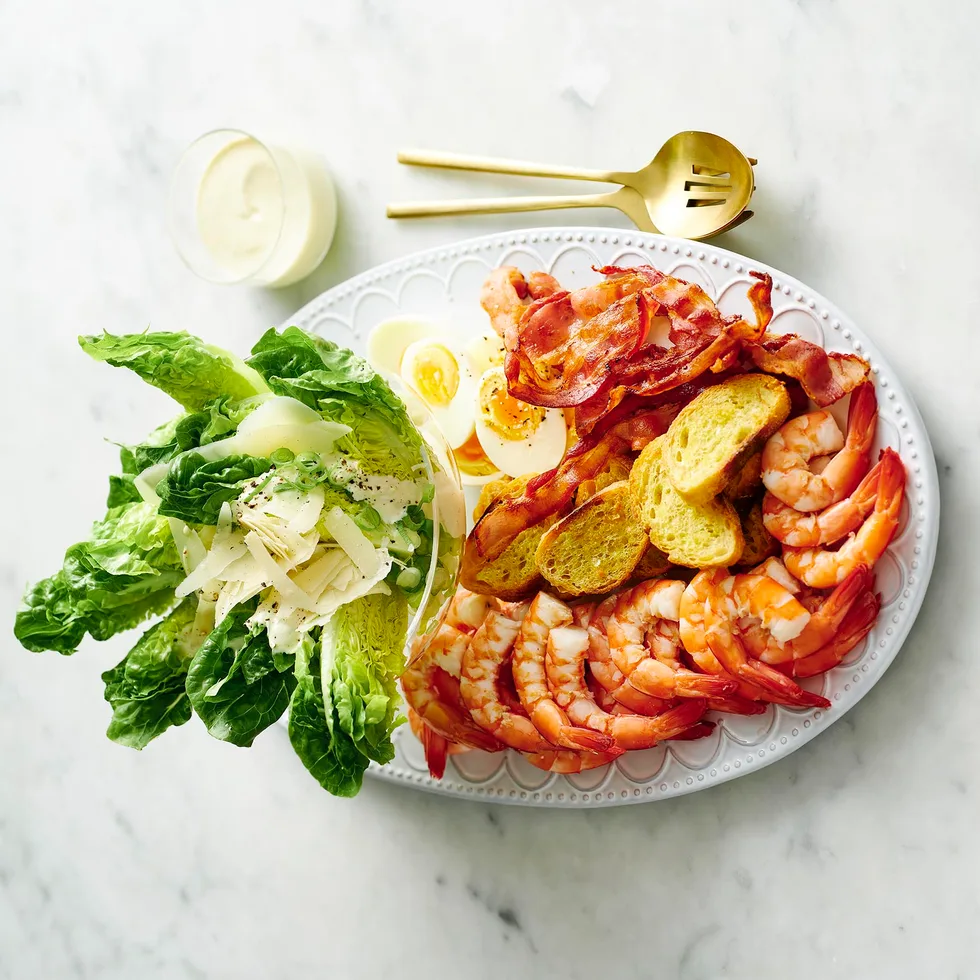 prawn and salad greens on a plate to form a prawn caesar salad