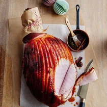 Glazed ham on a board with slices missing
