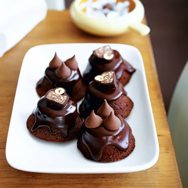 Little chocolate hazelnut cakes with ganache on a rectangular white plate