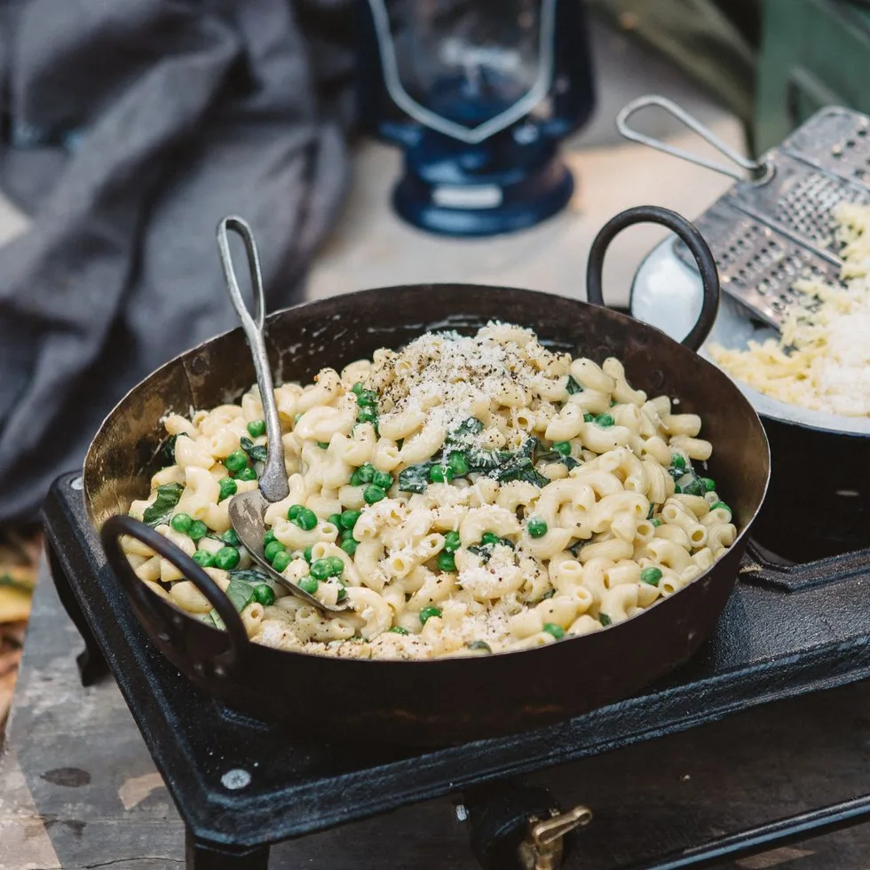 Mac and cheese cooking in a round pan on a camp stove.