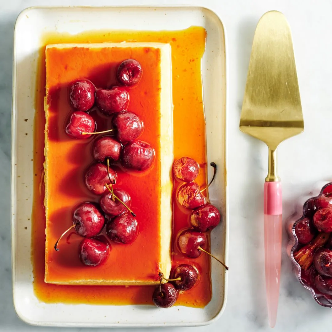 Vanilla flan with roasted cherries on a serving platter