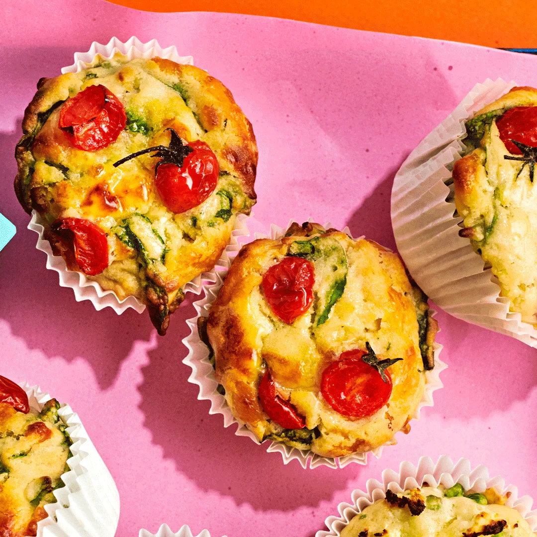 An aerial view of the top of tomato and cheese savoury muffins with spinach.