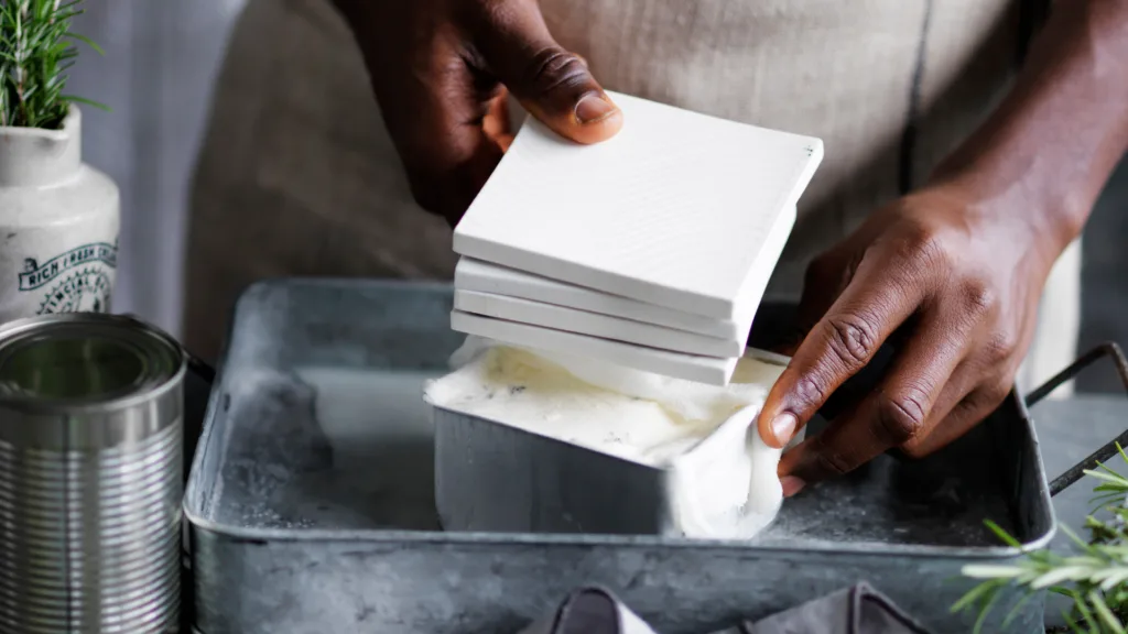 A person using weights to press down the haloumi curds into a small cake tin.