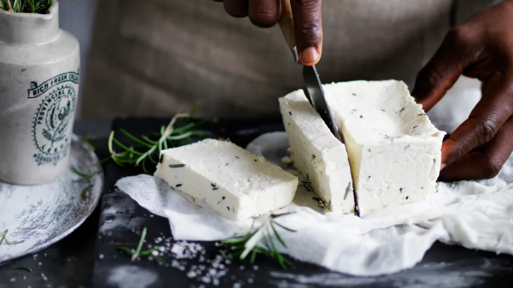 A person slicing the haloumi block with a knife, ready to cook it.