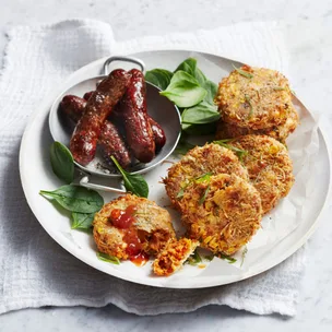 Cooked sausages on a round plate with sweet potato hash browns.