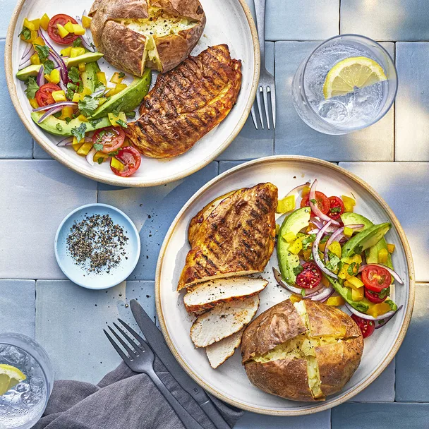 two plates with grilled chicken with avocado salad