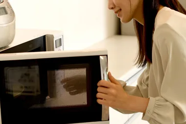 Woman opening microwave door making rice