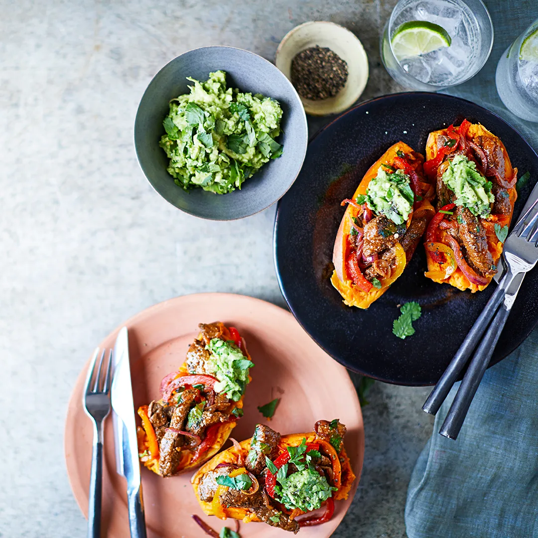 Baked sweet potato halves with steak filling and guacamole.