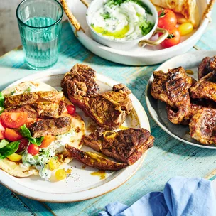 A pita wrap with lettuce, tomato and tzatziki and lamb chops on the side.