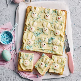Easter baking idea: A rectangular slab of blondies with white chocolate icing topped with white chocolate in the shape of rabbits - the perfect Easter baking treat!