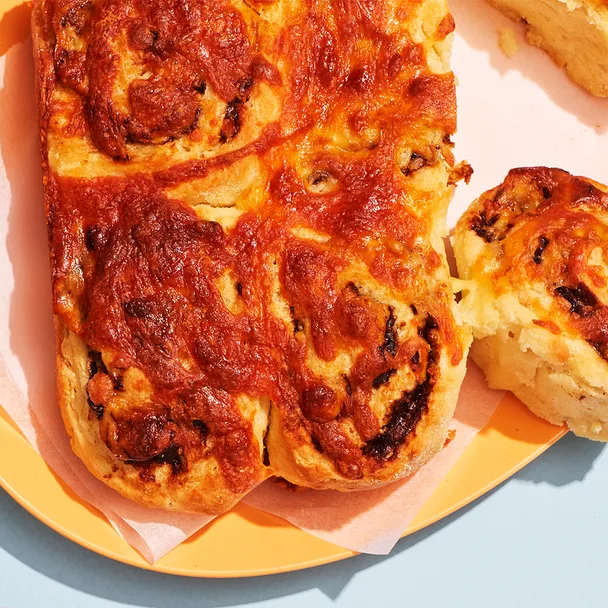 A group of cheese and vegemite scrolls with one broken off and ready to eat.