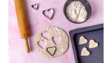 Flatlay of baking implements with some heart-shaped biscuits being made