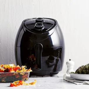 An air fryer with air fryer accessories: a basket and some tongs.