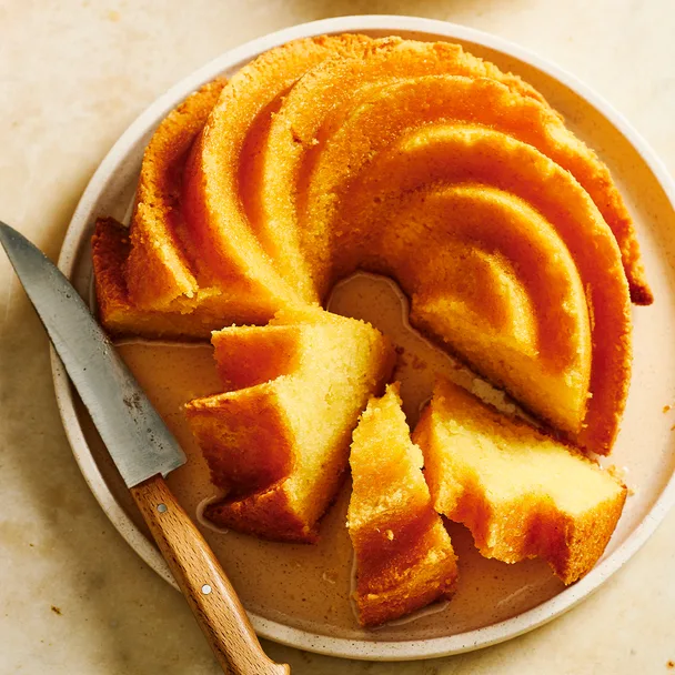 An almond bundt cake with citrus syrup drizzled over the top, cut into slices and ready to serve.