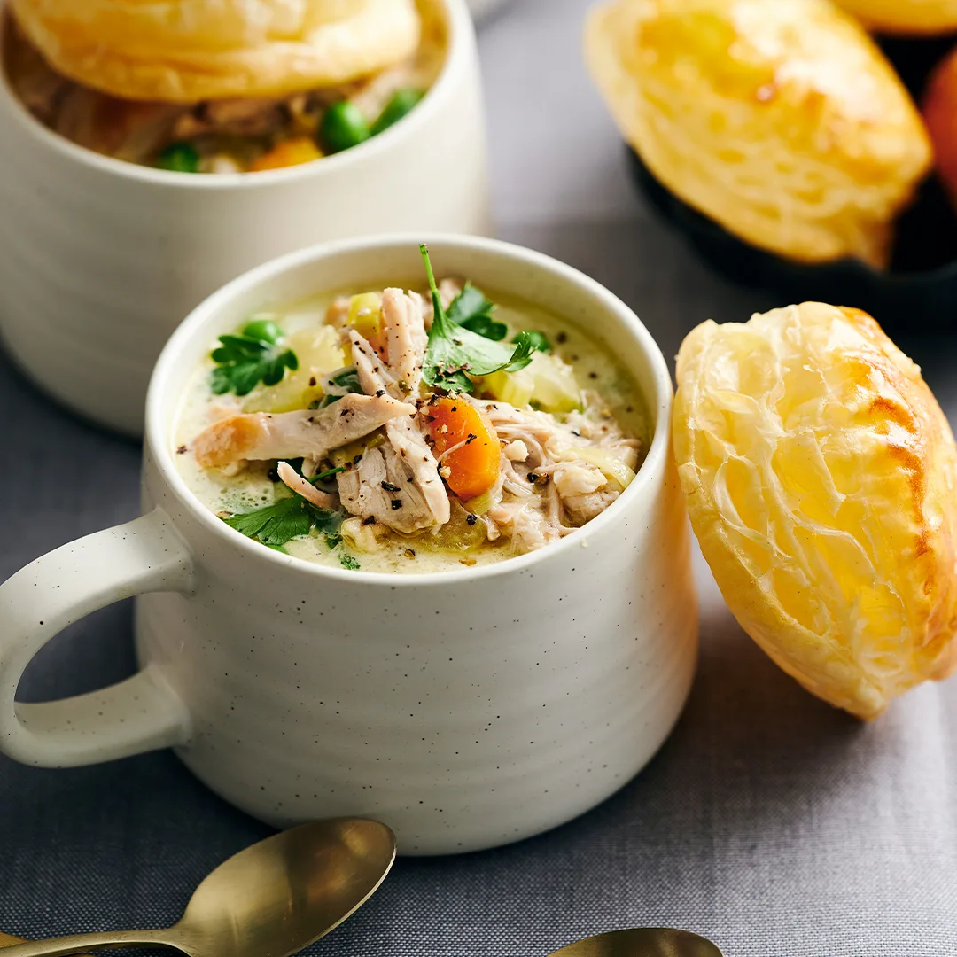 slow cooker chicken soup in a mug with pastry round on top
