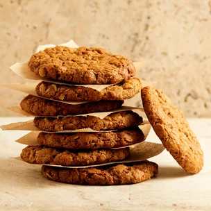 Gluten-free Anazc biscuits stacked up in a pile of seven, with one leaning to the side.