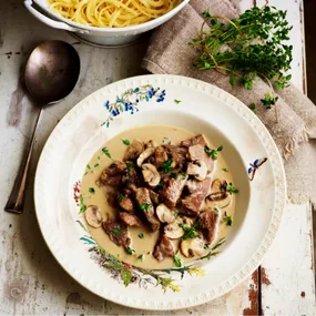 beef stroganoff in a white bowl with floral patterns