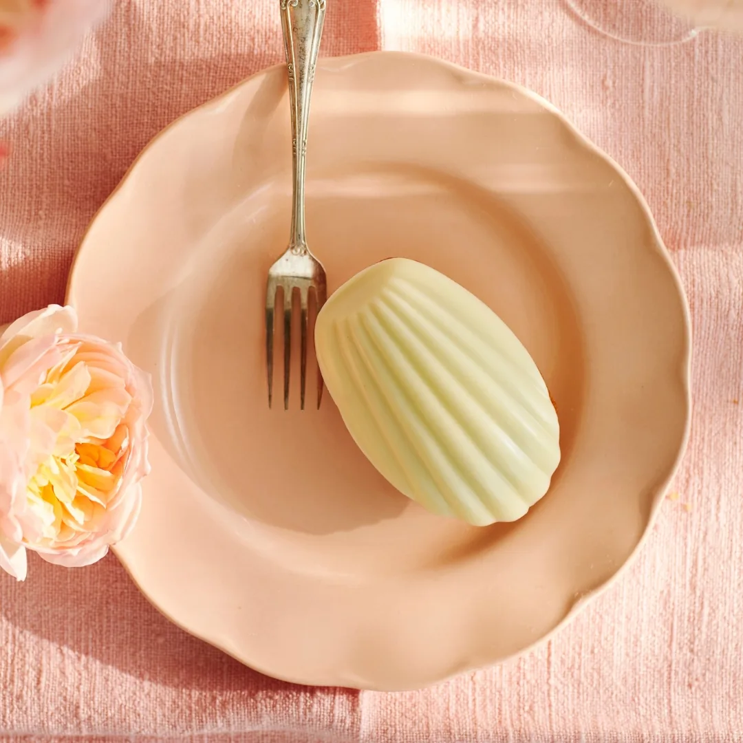 madeleines with a white chocolate topping on a pale pink plate with a fork