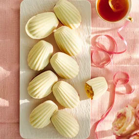 Madeleines with white chocolate coating on a white platter