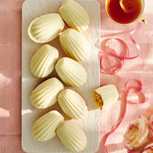 Madeleines with white chocolate coating on a white platter