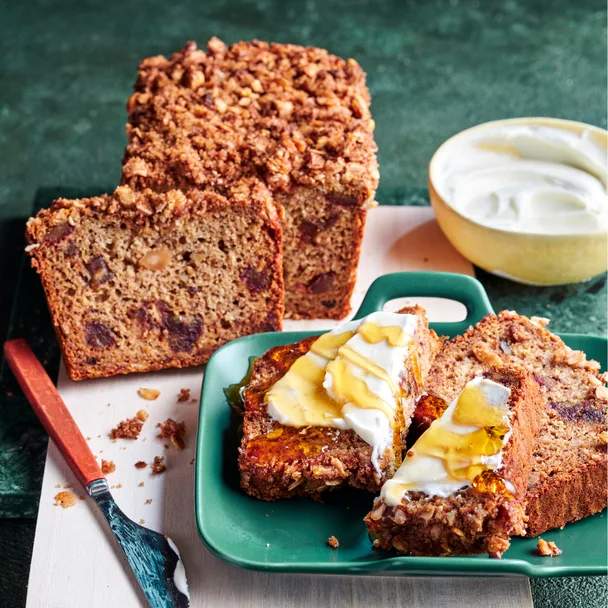 Banana date loaf with slices cut, served with yoghurt and honey.